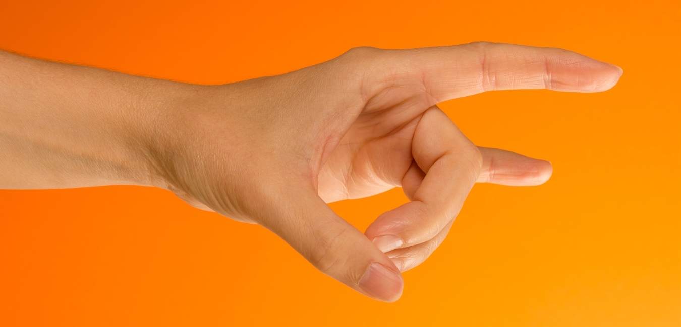 Mano formando un mudra budista sobre un fondo naranja